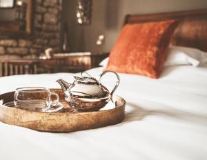 a tray with a tea kettle and glasses on a bed at Woolmarket House in Chipping Campden