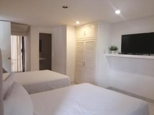 Habitación blanca con 2 camas y TV de pantalla plana. en Hotel del Paseo Campeche en Campeche