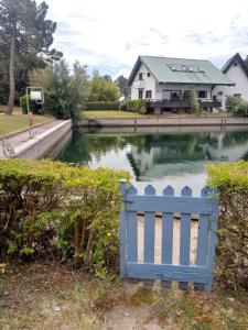 a blue gate in front of a lake with a house at RESIDENZA DI SANDRA in Isola Albarella