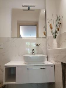 a white bathroom with a sink and a mirror at Loris House in Tropea