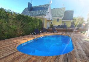 a swimming pool on a wooden deck with a house at Saulės Namai in Palanga