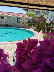 a swimming pool with purple flowers in front of a house at Sirius star otel in Ortaca