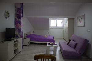a living room with a purple couch and a bed at Markulev Apartment in Ohrid