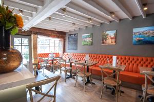 a restaurant with orange booths and tables and chairs at Woolmarket House in Chipping Campden