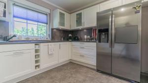 a kitchen with white cabinets and a stainless steel refrigerator at Ferienhaus Cottbus, Garage, große Sonnenterrasse, Kamin, 4 Zimmer, Ankleidezimmer in Cottbus