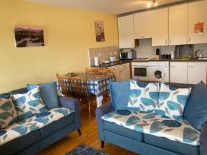 a living room with two blue couches and a kitchen at Harbour View at Sea Wharf Westport in Westport
