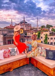 two women sitting on a bench on a balcony overlooking a city at Henna Hotel Istanbul in Istanbul