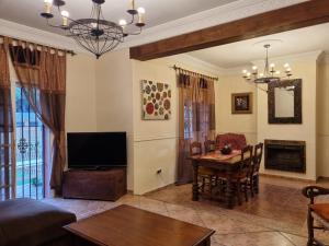 Una sala de estar con televisión y una mesa de comedor. en VACACIONES DE LUJO.CHALET PISCINA Y PLAYA.EL PUERTO, en El Puerto de Santa María