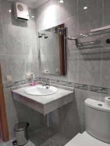 y baño con lavabo, aseo y espejo. en Apartamento Con Piscina en Fonte de Ons4, en A Revolta