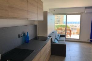 a living room with a couch and a kitchen with a view at L'EFFET MER, DUPLEX SUR LE PORT AVEC SES 2 TERRASSES VUE MER in Hyères