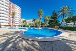 a large swimming pool with palm trees and a building at Apartamento Laura in Alcudia +15 photos