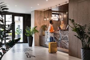 a woman with a yellow suitcase standing in front of a counter at Hotel Raymond in Truskavets