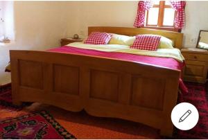 Un dormitorio con una gran cama de madera con almohadas rojas en Etno guest house Lalovic, en Tjentište