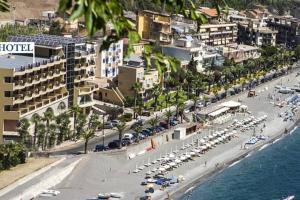 a beach with a bunch of umbrellas and buildings at Casa vacanze STEVIA in Santa Margherita-Sant'Alessio Siculo
