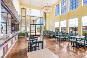 a dining room with tables and chairs and windows at Hotel Hacienda at Ontario Ranch in Ontario