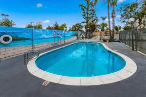 a swimming pool with blue water and a fence at Hotel Hacienda at Ontario Ranch in Ontario