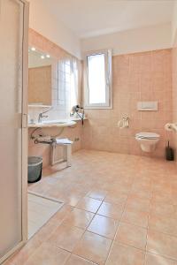 łazienka z umywalką, toaletą i wanną w obiekcie Hotel La Perla w Lignano Sabbiadoro