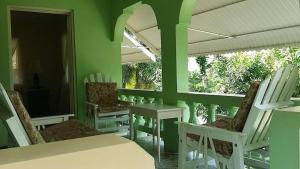 a green room with white chairs and tables and windows at Rock Side Villa On the Beach in Treasure Beach