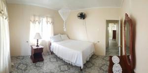 a bedroom with a white bed and a lamp and window at Rock Side Villa On the Beach in Treasure Beach