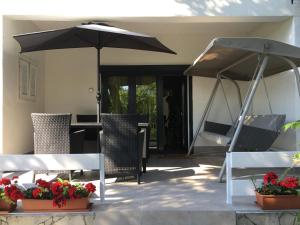 un patio con sombrilla, sillas y mesa en Nefelejcs Apartman, en Balatonvilágos