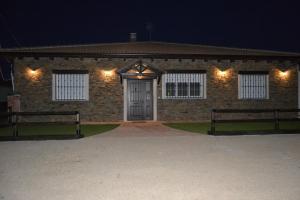 a brick building with two benches in front of it at night at El Capricho de los Carrascos in Juarros de Voltoya