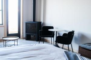 a bedroom with a bed and chairs and a stove at Bowline Hotel in Astoria, Oregon