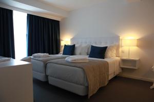 a hotel room with a large bed with blue pillows at Hotel Anjo de Portugal in Fátima