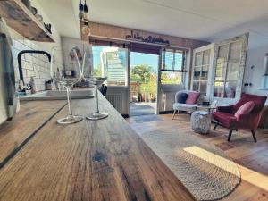 B&B Duinbrink في دن هيلدر: غرفة معيشة مع طاولة خشبية عليها أكواب