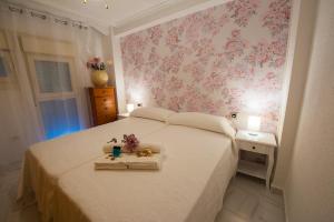 a bedroom with a white bed with pink floral wallpaper at Las Damas Premium 23F Beach Front - Pool & Parking in Benidorm
