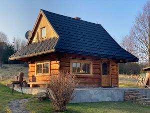 eine kleine Blockhütte mit schwarzem Dach in der Unterkunft Domek Wałacha in Istebna