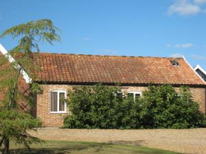 a brick house with a red roof at Colston Hall Cottages in Framlingham