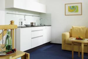 a kitchen with white cabinets and a table and a chair at Apartment-Hotel Schaffenrath in Salzburg