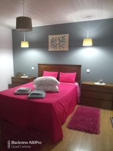 マセド・デ・カヴァレイロスにあるCasa do Terreiroのピンクのシーツと枕が付いたピンクベッド付きのベッドルーム1室が備わります。
