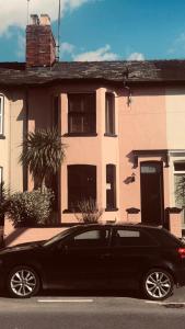 a black car parked in front of a house at Suffolk pink house, Newmarket town centre in Newmarket