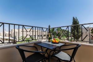 Un balcón con mesa y 2 sillas y un bol de fruta en Canary Boutique Hotel, en Amán