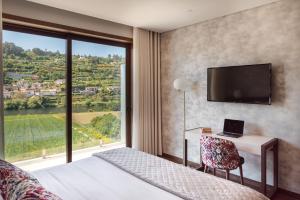 a bedroom with a bed and a desk and a large window at Quinta de Santo António - Country House & Villas in Marco de Canavezes