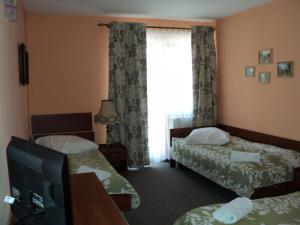 a hotel room with two beds and a television at Hotel Primagor in Szydłowiec