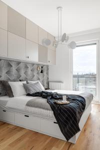 a white bedroom with a large bed and a window at CITYSTAY Dluga Grobla Gdansk Apartment with Sauna in Gdańsk