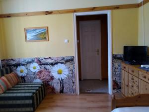 a living room with a couch and flowers on the wall at 4 Évszak Apartman in Gyula