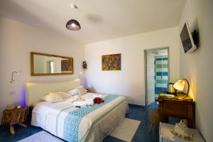 sypialnia z łóżkiem, stołem i lustrem w obiekcie Suites Voce del Mare w mieście Tertenìa