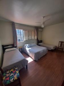 a bedroom with two beds and a window at Pousada São Francisco in Bento Gonçalves