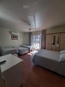 um quarto de hotel com três camas e uma janela em Pousada São Francisco em Bento Gonçalves