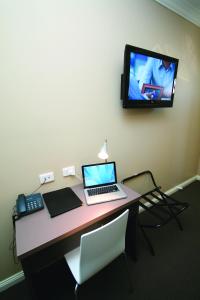 einen Schreibtisch mit einem Laptop und einem TV an der Wand in der Unterkunft Sundowner Motel Hotel in Whyalla