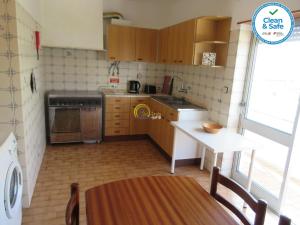 a small kitchen with wooden cabinets and a table at Sol e Praia - Peniche II in Peniche