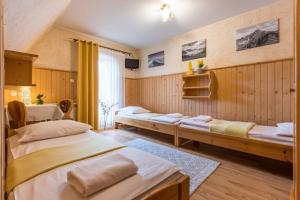 Dos camas en una habitación con paredes de madera. en Gościniec Nad Potokiem, en Małe Ciche