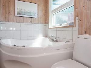 uma casa de banho branca com uma banheira e um WC em 6 person holiday home in R m em Lakolk