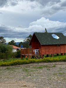 Cette cabane en rondins dispose d'un toit mansardé et d'une terrasse couverte. dans l'établissement GLAMPING VILLA PALVA en VILLA DE LEYVA, à Villa de Leyva