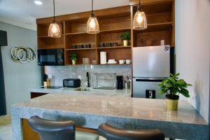 a kitchen with a counter with chairs and a refrigerator at Rio Suites in Tijuana
