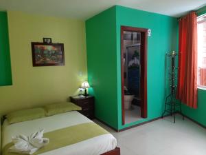 a bedroom with green walls and a blue door at Hostal Balcon del Cielo in Baños