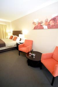 Sundowner Motel Hotel في وايالا: غرفه فندقيه بسرير وكرسيين